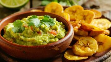 recién hecho guacamole es además un golpear con un insinuación de Lima jugo y cilantro servido junto a crujiente plátano papas fritas para un tropical giro en un clásico aperitivo foto