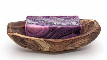 A handcrafted wooden soap dish holds a bar of artisan soap swirled with layers of deep purple and shimmery silver photo