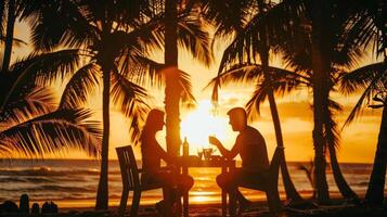 A couple enjoying a romantic dinner under a canopy of palm trees with the setting sun casting a warm glow over the scene photo