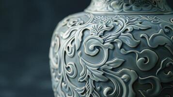 A closeup of a ceramic vase reveals the detailed carvings of swirling vines and leaves. photo