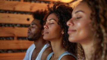 Tres amigos sentar con su ojos cerrado completamente presente en el meditativo atmósfera de el sauna. foto