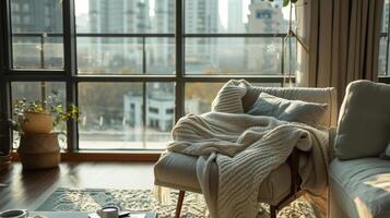 A cozy living room with a large window overlooking the city featuring a cashmere throw thrown over a comfortable armchair photo