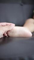 Close-up of a father's hand holding his son's foot. Slow motion video