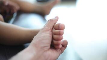 Close-up of a father's hand holding his son's foot. Slow motion video