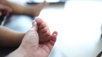 Close-up of a father's hand holding his son's foot. Slow motion video