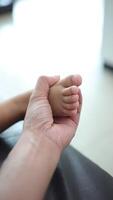 Nahansicht von ein Vaters Hand halten seine Söhne Fuß. schleppend Bewegung video