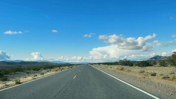 deserto viaggio. strada attraverso arido montagne, un vuoto strada principale attraverso un' sereno deserto paesaggio con aspro montagne sotto un' vasto cielo. video