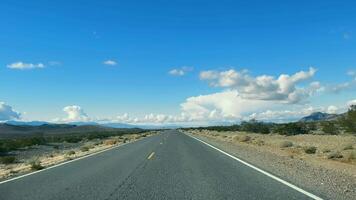 Desert Journey. Road Through Arid Mountains, An empty road leading through a serene desert landscape with rugged mountains under a vast sky. video