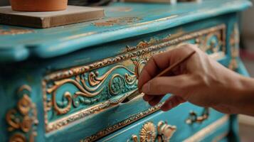 In progress shot of a dresser being handpainted in a vibrant teal color with intricate designs being carefully added by an artists brush photo