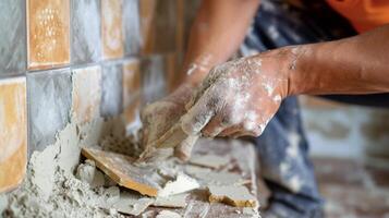 An expert tiler carefully chiseling away damaged tiles to make way for new ones seamlessly blending them in with the existing ones in a bathroom photo