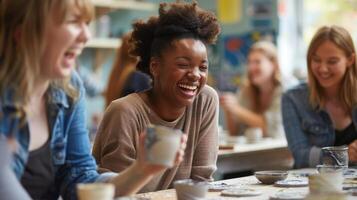 A group of friends sitting around a table laughing and working on their own ceramic coaster designs. photo