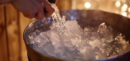 A person holding an ice bucket getting ready to pour freezing water onto themselves after a sauna session. photo