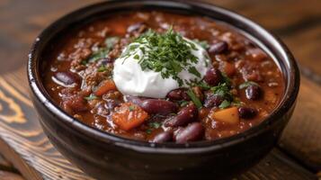 A tantalizing bowl of chili bursting with shades of crimson and hints of orange topped with a generous dollop of sour cream to offset the blazing heat. This is chili at it photo