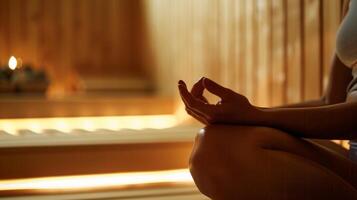 A person sitting in the sauna hands resting lightly on their stomach as they focus on their breath and let the heat envelop them guiding them to a state of complete mindfulness. photo