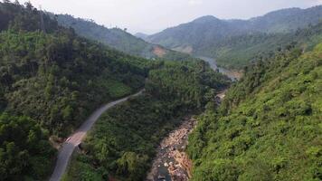 antenn antal fot visa upp de frodig, grönskande landskap av de annamit räckvidd i vietnam, med en lindning väg skärande genom de tät tropisk skog video