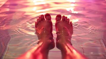 A persons feet immersed in a shallow pool of water beneath an infrared heat lamp providing relief to their arthritic toes and ankles. photo