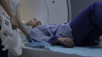 A young girl patient in specialized clothing falls on a magnetic resonance imaging device. Close-up video