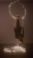 Woman Aerialist Hangs Upside Down from Ring Decorated Glowing Christmas Garland video