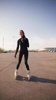 bak- se smal kvinna med skön figur rullskridskor på asfalt i stad parkera video