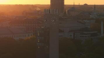 Aerial panoramic sunset over Riga old town in Latvia. Beautiful spring sunset over Riga. Riga clock tower close up view near the train station. Golden hour fire sunset. video