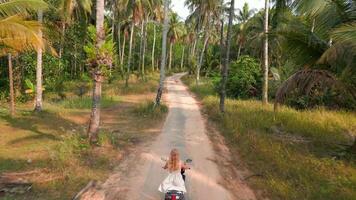 Caucasian woman riding a scooter on a tropical island in Thailand. video