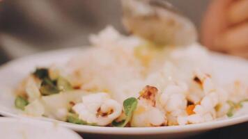 giovane donna godendo frutti di mare piatto durante il tramonto nel il spiaggia ristorante video