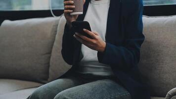 Jeune asiatique femme, numérique nomade travail à distance de une café, en buvant café et en utilisant ordinateur portable, souriant. video