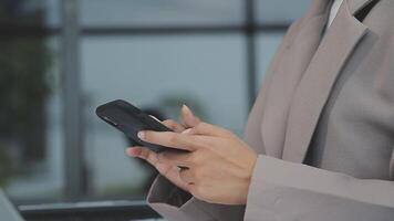 femme d'affaires asiatique en costume formel au bureau heureuse et joyeuse lors de l'utilisation d'un smartphone et du travail video