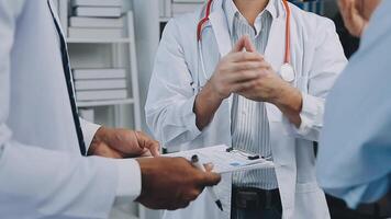 Multiracial medical team having a meeting with doctors in white lab coats and surgical scrubs seated at a table discussing a patients records, Medical team checking Xray results. video