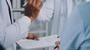 Multiracial medical team having a meeting with doctors in white lab coats and surgical scrubs seated at a table discussing a patients records, Medical team checking Xray results. video