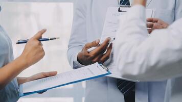 Multiracial medical team having a meeting with doctors in white lab coats and surgical scrubs seated at a table discussing a patients records, Medical team checking Xray results. video