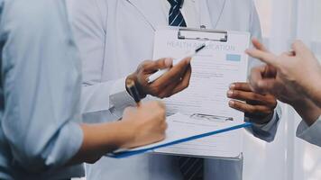 Multiracial medical team having a meeting with doctors in white lab coats and surgical scrubs seated at a table discussing a patients records, Medical team checking Xray results. video