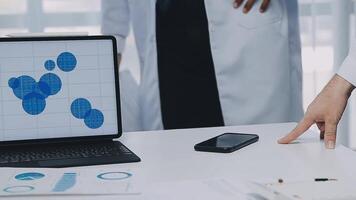 Multiracial medical team having a meeting with doctors in white lab coats and surgical scrubs seated at a table discussing a patients records, Medical team checking Xray results. video