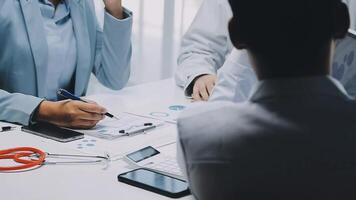 Multiracial medical team having a meeting with doctors in white lab coats and surgical scrubs seated at a table discussing a patients records, Medical team checking Xray results. video