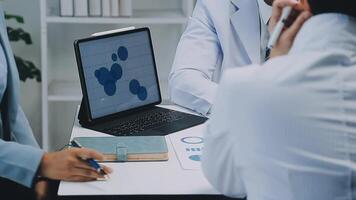 Multiracial medical team having a meeting with doctors in white lab coats and surgical scrubs seated at a table discussing a patients records, Medical team checking Xray results. video