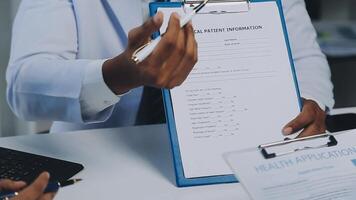 Multiracial medical team having a meeting with doctors in white lab coats and surgical scrubs seated at a table discussing a patients records, Medical team checking Xray results. video