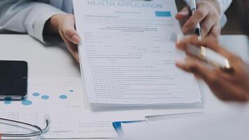 Multiracial medical team having a meeting with doctors in white lab coats and surgical scrubs seated at a table discussing a patients records, Medical team checking Xray results. video