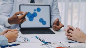 Multiracial medical team having a meeting with doctors in white lab coats and surgical scrubs seated at a table discussing a patients records, Medical team checking Xray results. video