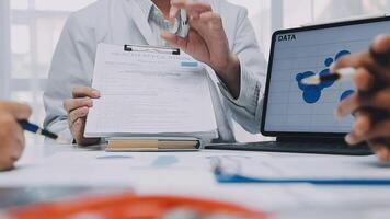 Multiracial medical team having a meeting with doctors in white lab coats and surgical scrubs seated at a table discussing a patients records, Medical team checking Xray results. video