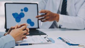 Multiracial medical team having a meeting with doctors in white lab coats and surgical scrubs seated at a table discussing a patients records, Medical team checking Xray results. video