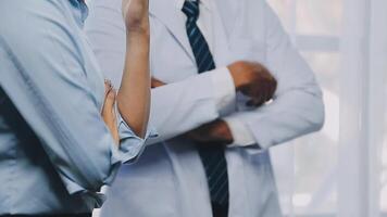 multirracial médico equipo teniendo un reunión con doctores en blanco laboratorio abrigos y quirúrgico matorrales sentado a un mesa que se discute un pacientes registros, médico equipo comprobación radiografía resultados. video