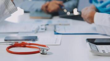 Multiracial medical team having a meeting with doctors in white lab coats and surgical scrubs seated at a table discussing a patients records, Medical team checking Xray results. video