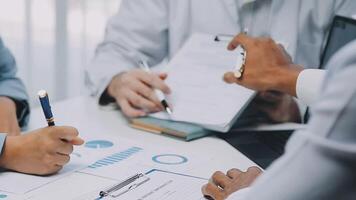 Multiracial medical team having a meeting with doctors in white lab coats and surgical scrubs seated at a table discussing a patients records, Medical team checking Xray results. video