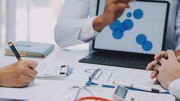 Multiracial medical team having a meeting with doctors in white lab coats and surgical scrubs seated at a table discussing a patients records, Medical team checking Xray results. video