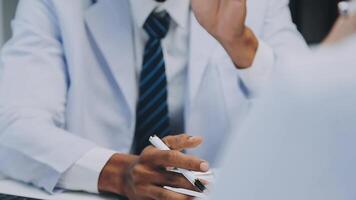 Multiracial medical team having a meeting with doctors in white lab coats and surgical scrubs seated at a table discussing a patients records, Medical team checking Xray results. video