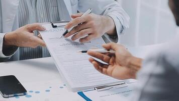 Multiracial medical team having a meeting with doctors in white lab coats and surgical scrubs seated at a table discussing a patients records, Medical team checking Xray results. video