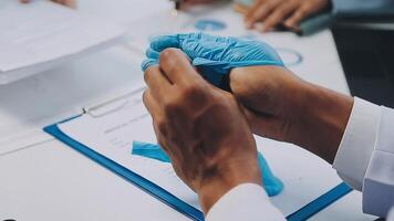 Multiracial medical team having a meeting with doctors in white lab coats and surgical scrubs seated at a table discussing a patients records, Medical team checking Xray results. video