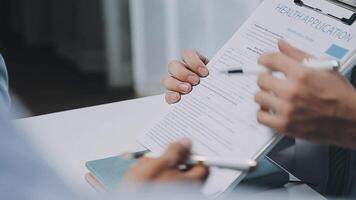 Multiracial medical team having a meeting with doctors in white lab coats and surgical scrubs seated at a table discussing a patients records, Medical team checking Xray results. video