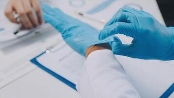 Multiracial medical team having a meeting with doctors in white lab coats and surgical scrubs seated at a table discussing a patients records, Medical team checking Xray results. video