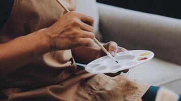 plus de le épaule sélectif concentrer coup de Masculin artiste en utilisant brosse tandis que ajouter Couleur peindre à crayon dessin sur Toile video